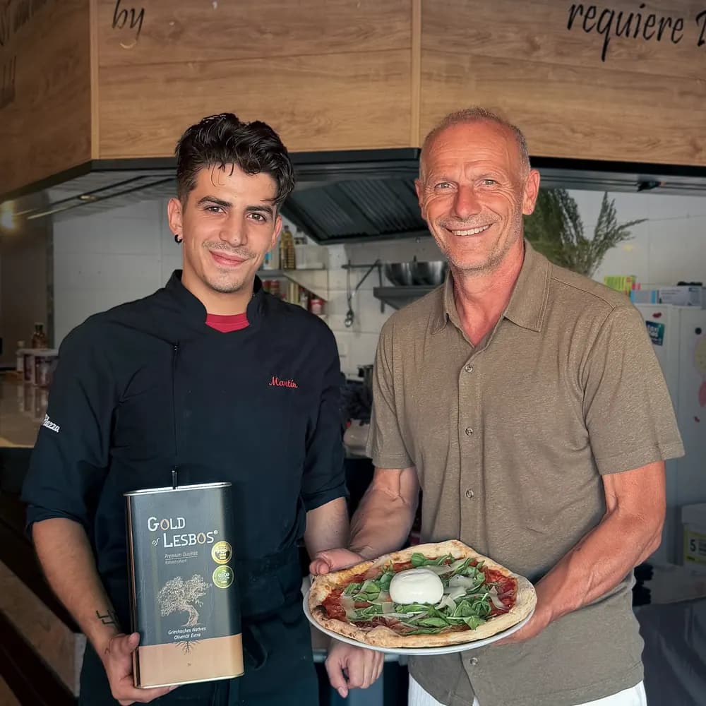 Küchenchef Martin Pérez und Produzent Anastasios Fortomaris in der Küche des Restaurants La Piazza mit einem Drei-Liter-Kanister Gold of Lesbos und einer frisch gebackenen Pizza